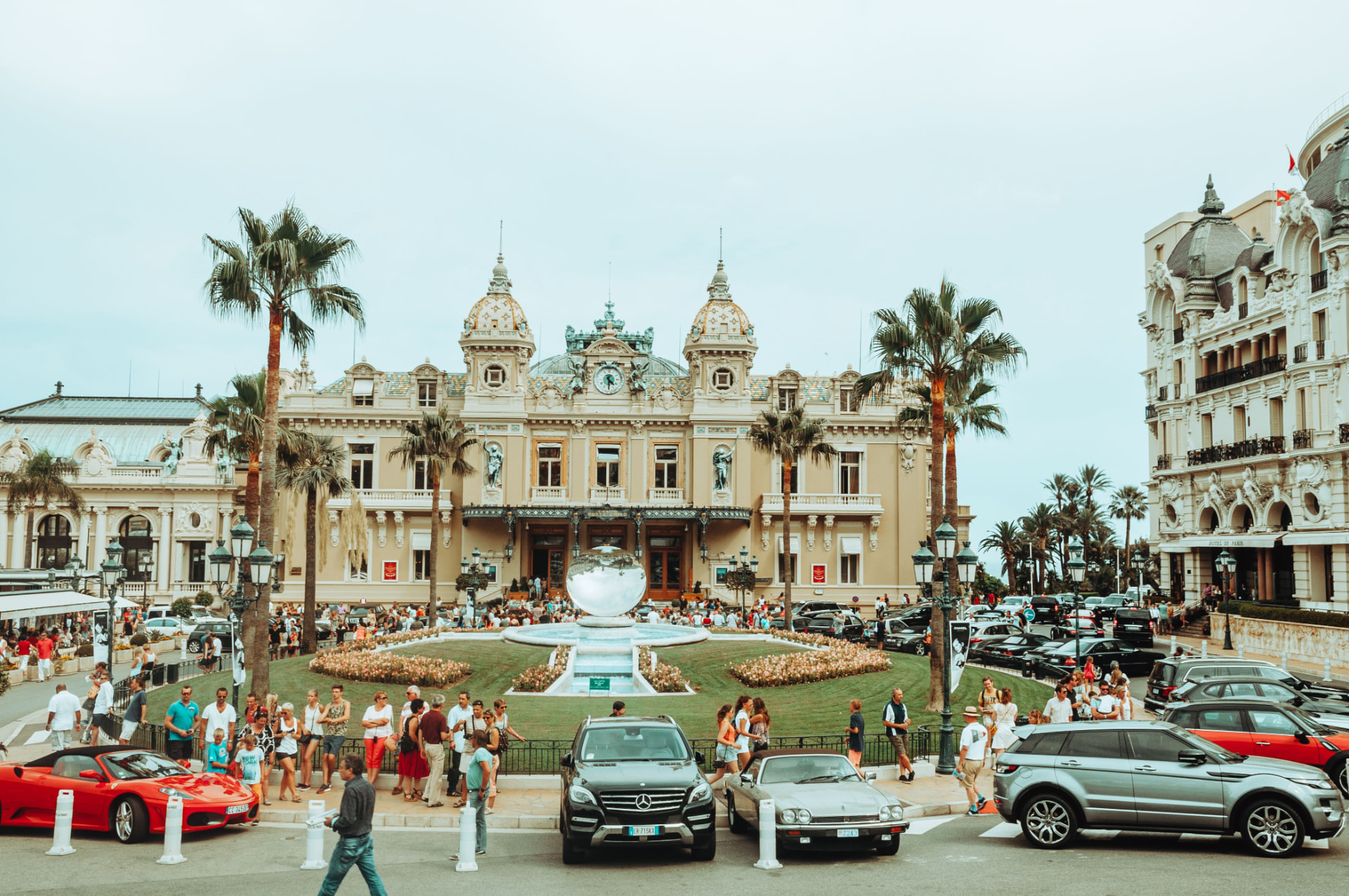 The ornate Belle Époque facade of the Casino de Monte-Carlo with its green-patina domes, framed by palm trees and a splashing fountain